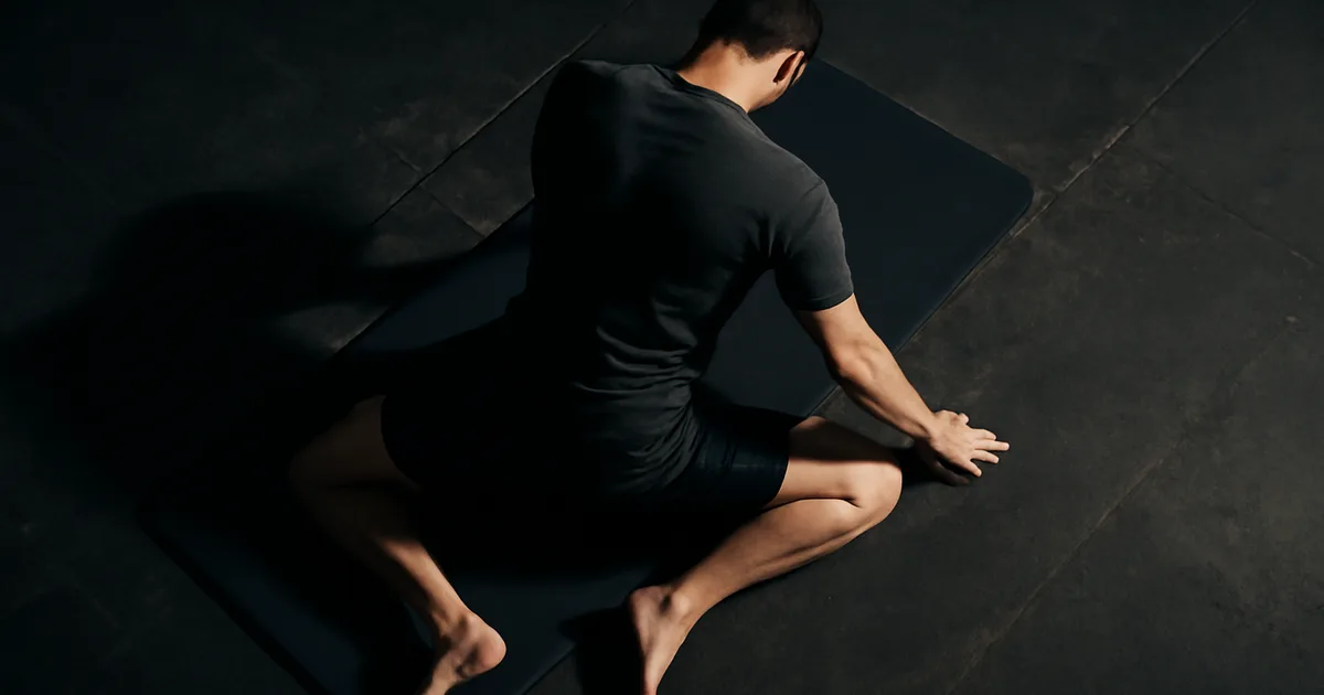 Athlète en position 90/90 stretch hanche sur tapis de sol noir