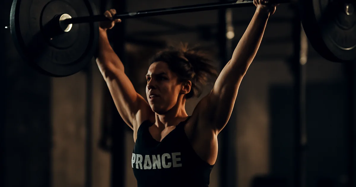 Athlète féminine française en plein clean & jerk, ambiance box hardcore